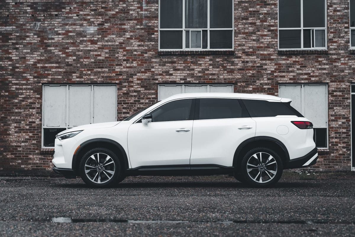 2020 Toyota Highlander XLE in Blizzard White, full side profile in front of a brick warehouse