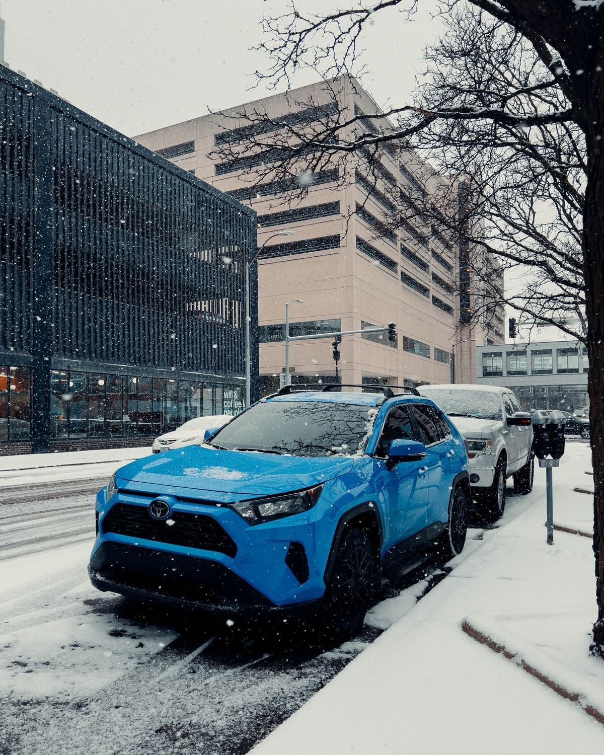 2021 Toyota RAV4 XSE Hybrid in Blueprint Blue with black wheels, front three-quarter view on a snowy street